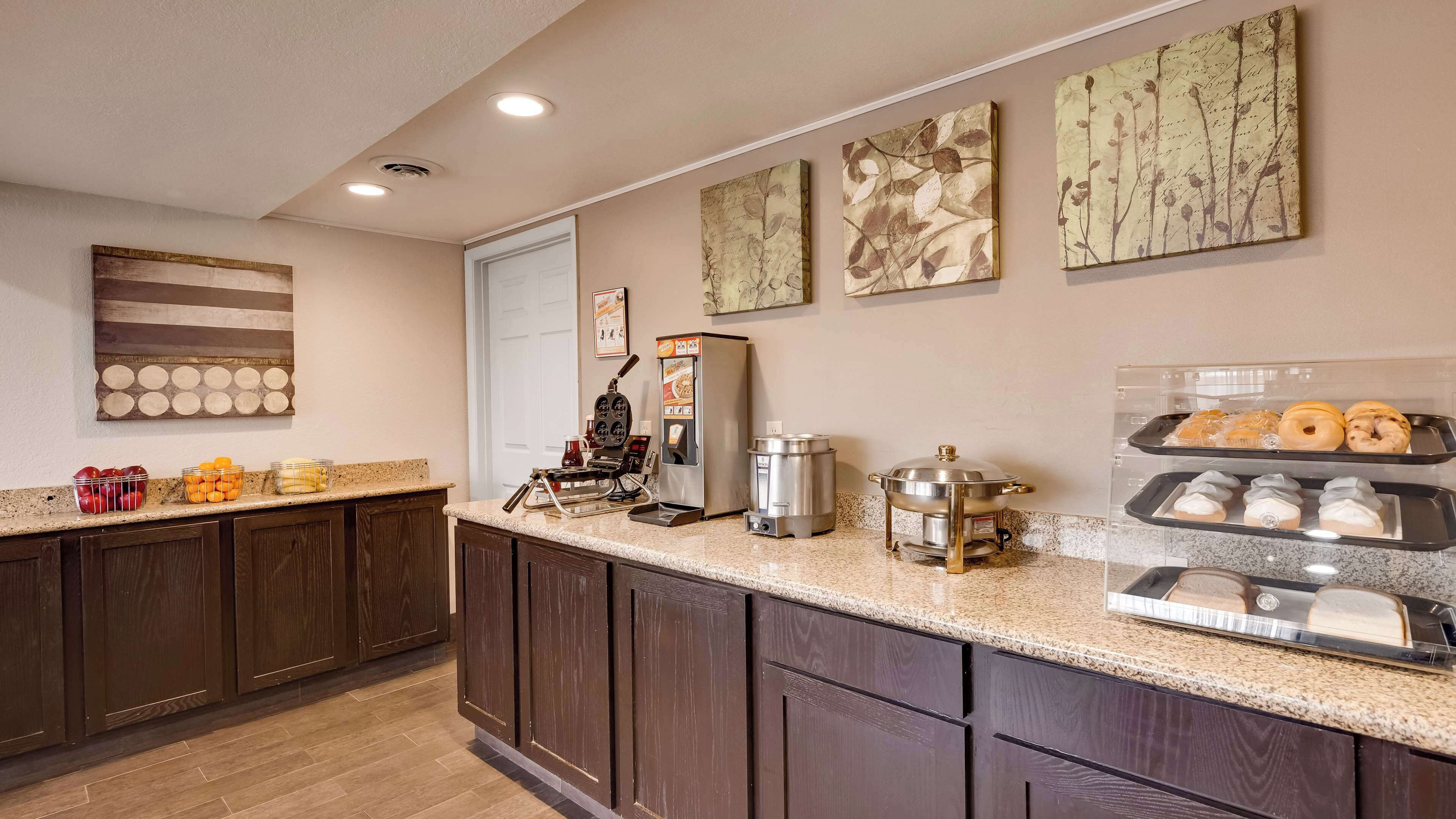 A kitchen with a coffee machine, a kettle, and a food display.