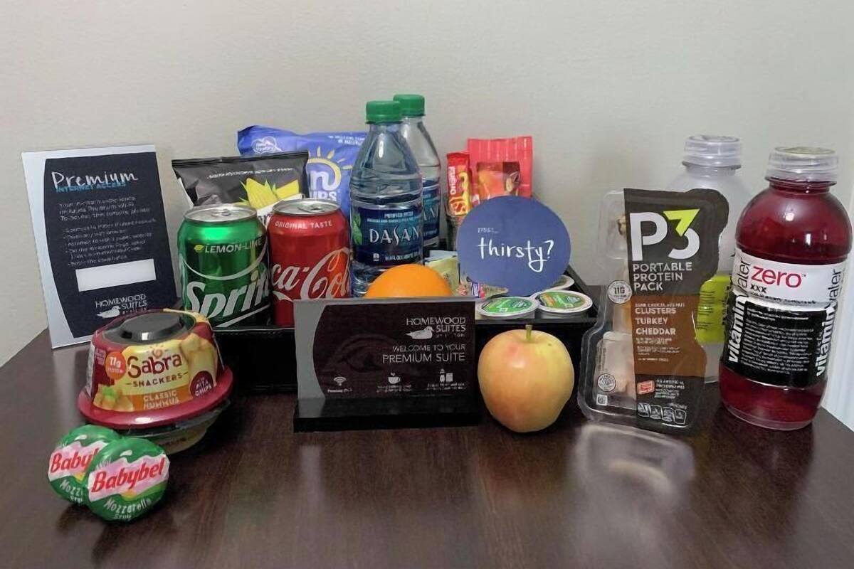 Un assortiment de boissons et de collations, ainsi qu’un panneau d’accueil sur une table.