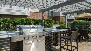 Une cuisine extérieure équipée d’un barbecue, d’un four encastré et d’un coin bar.