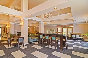 A spacious lobby with a checkered floor, a bar area, seating arrangements, and a fireplace.
