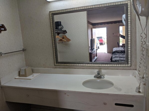 Une salle de bain équipée d’un lavabo, d’un miroir et d’un sèche-cheveux fixé au mur.
