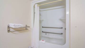 A bathroom with a white bathtub, a shower curtain, a towel rack with folded towels, and a grab bar for support.