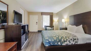 Una habitación de hotel con cama, televisión, escritorio y silla.