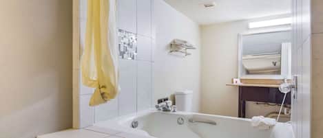 A modern bathroom with a large bathtub, a showerhead, and a toilet.