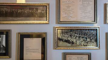 Paredes com fotografias históricas e documentos emoldurados, incluindo um menu do Hotel Rocket Room Savvy.