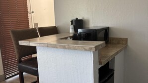 Un petit coin cuisine comprenant un plan de travail, une machine à café et un four à micro-ondes.