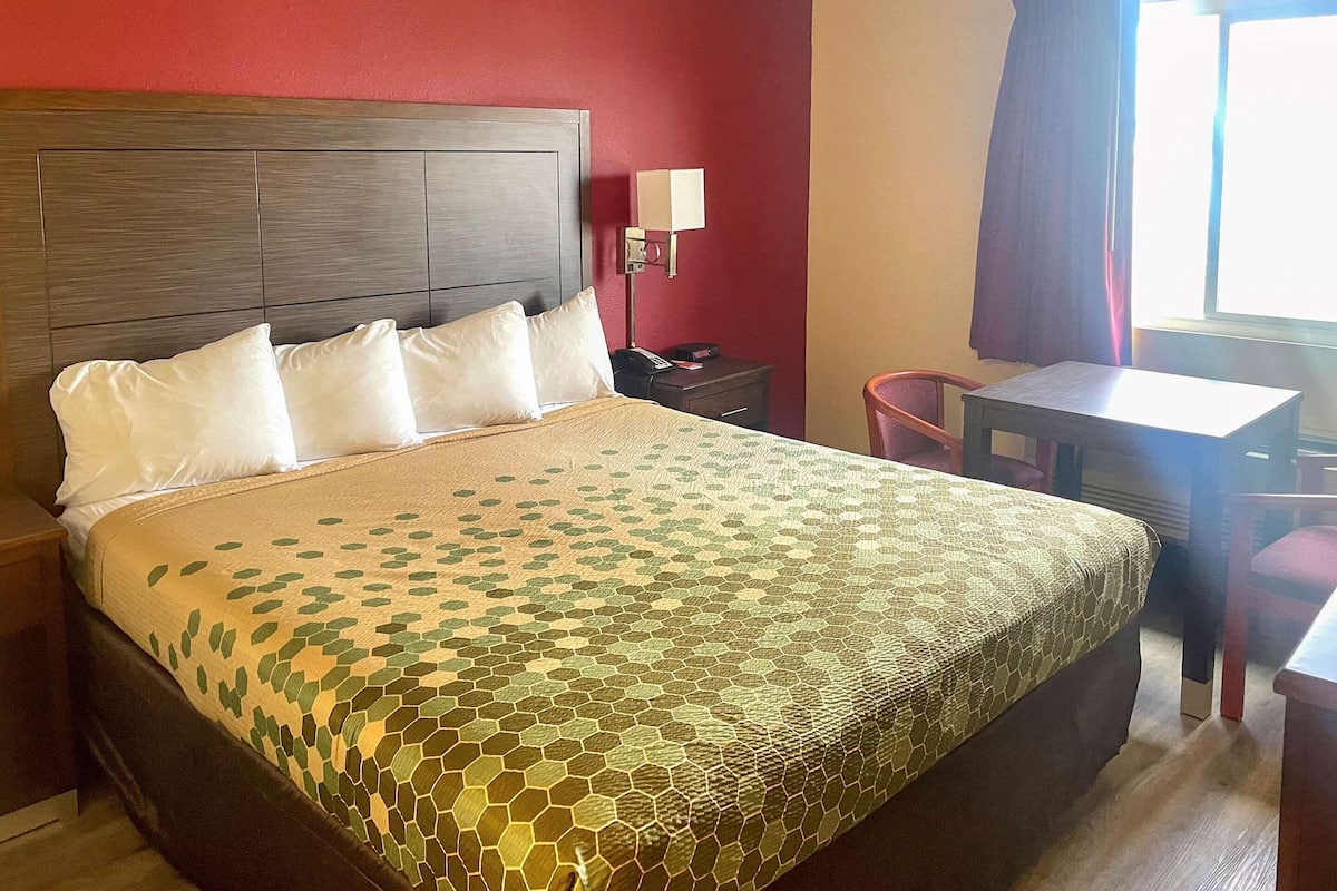 A hotel room with a large bed, a desk, and a chair.