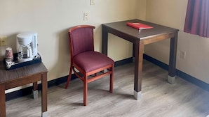 A small room with a wooden chair, a coffee maker, and a table with a red folder. - Econo Lodge Inn & Suites Corning Travel Center (Corning)