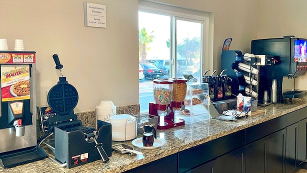 A breakfast bar with a waffle maker, coffee machines, and a complimentary breakfast sign. - Econo Lodge Inn & Suites Corning Travel Center (Corning)