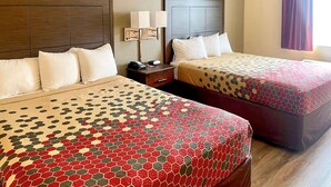 A hotel room with two beds, each with a patterned bedspread, a nightstand with a lamp, and a window with curtains. - Econo Lodge Inn & Suites Corning Travel Center (Corning)