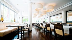 Un restaurante espacioso con techos altos, varias mesas de comedor y sillas dispuestas en filas.