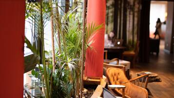 A cozy indoor seating area with a wooden table, a cushioned chair, and a red pillar.