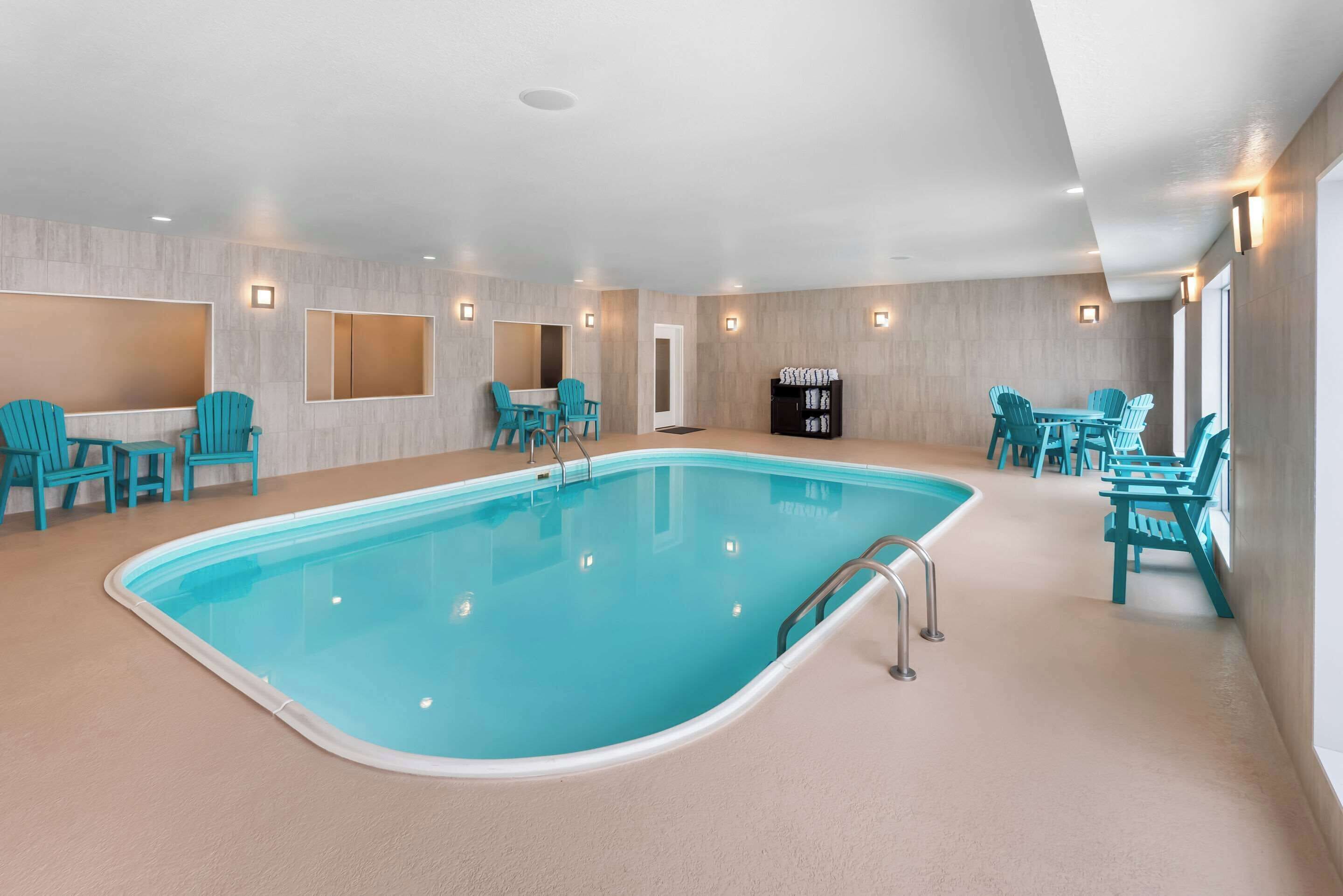 Une piscine intérieure avec des chaises turquoise et un meuble noir.