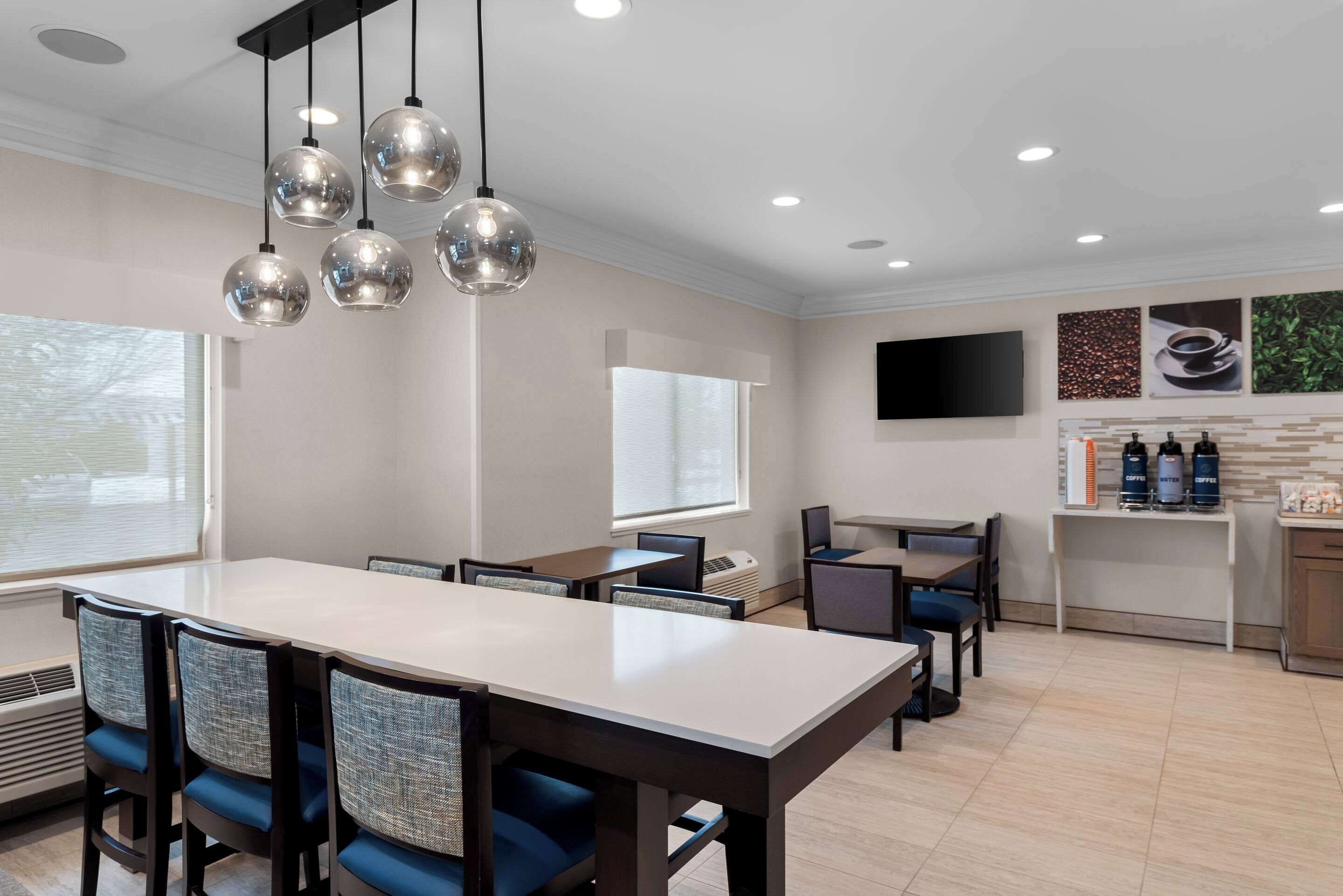 A modern meeting room with a long table, chairs, and a ceiling light fixture.