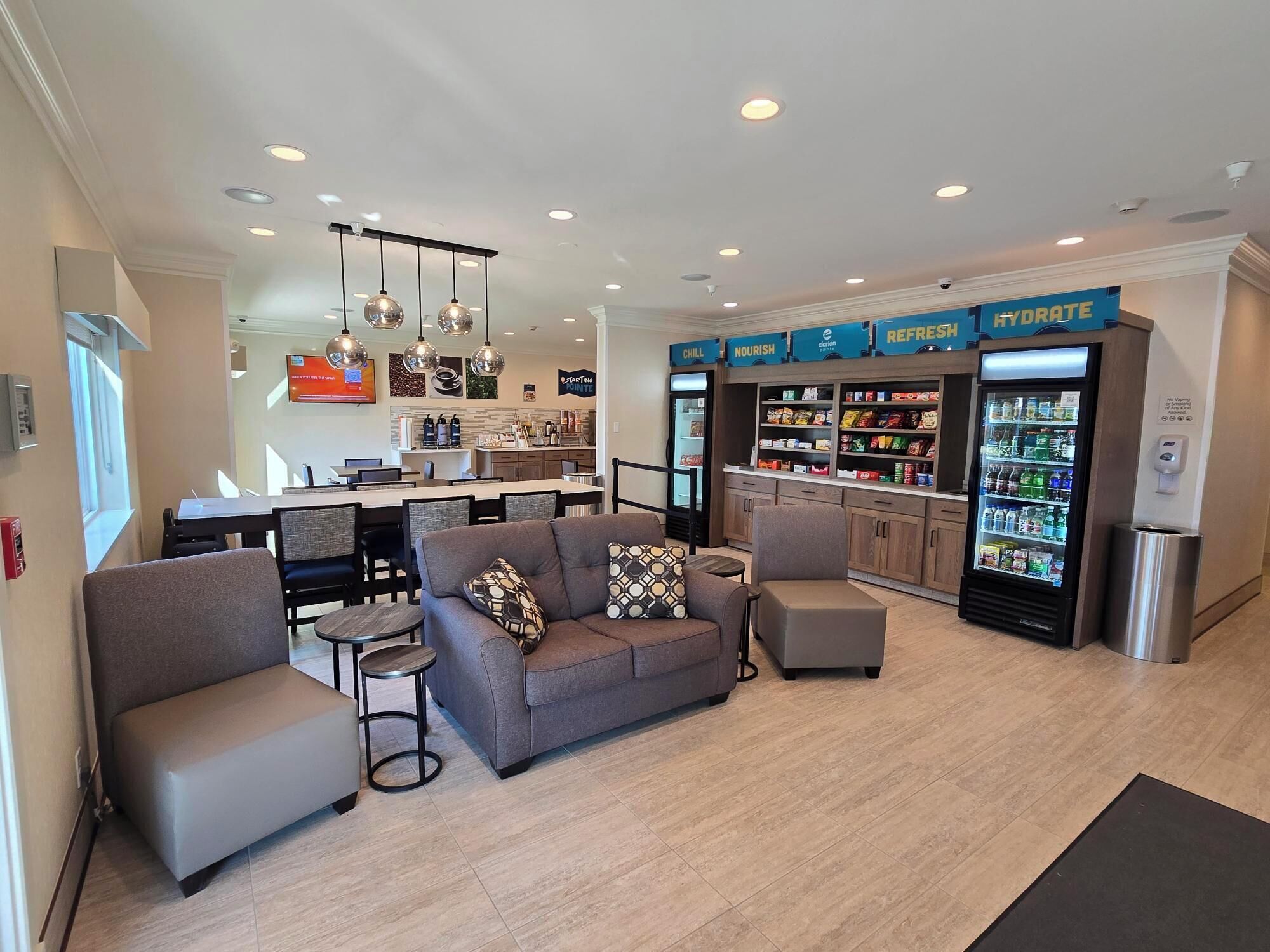 A modern hotel lobby with a seating area, a kitchenette, and a refreshment bar.