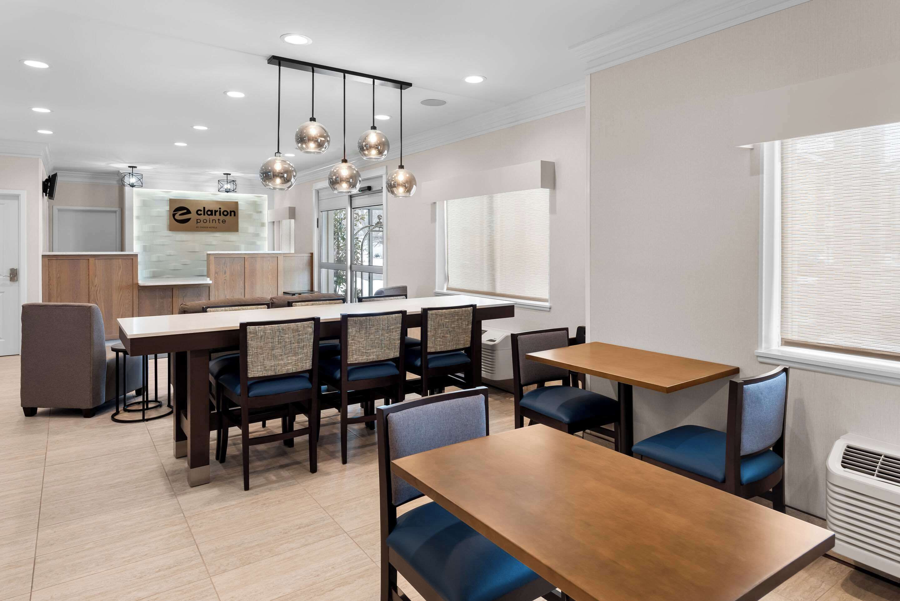 A modern hotel lobby with a reception desk, seating area, and large windows.