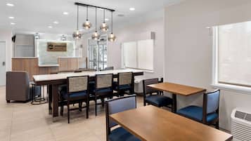A modern hotel lobby with a reception desk, seating area, and large windows.