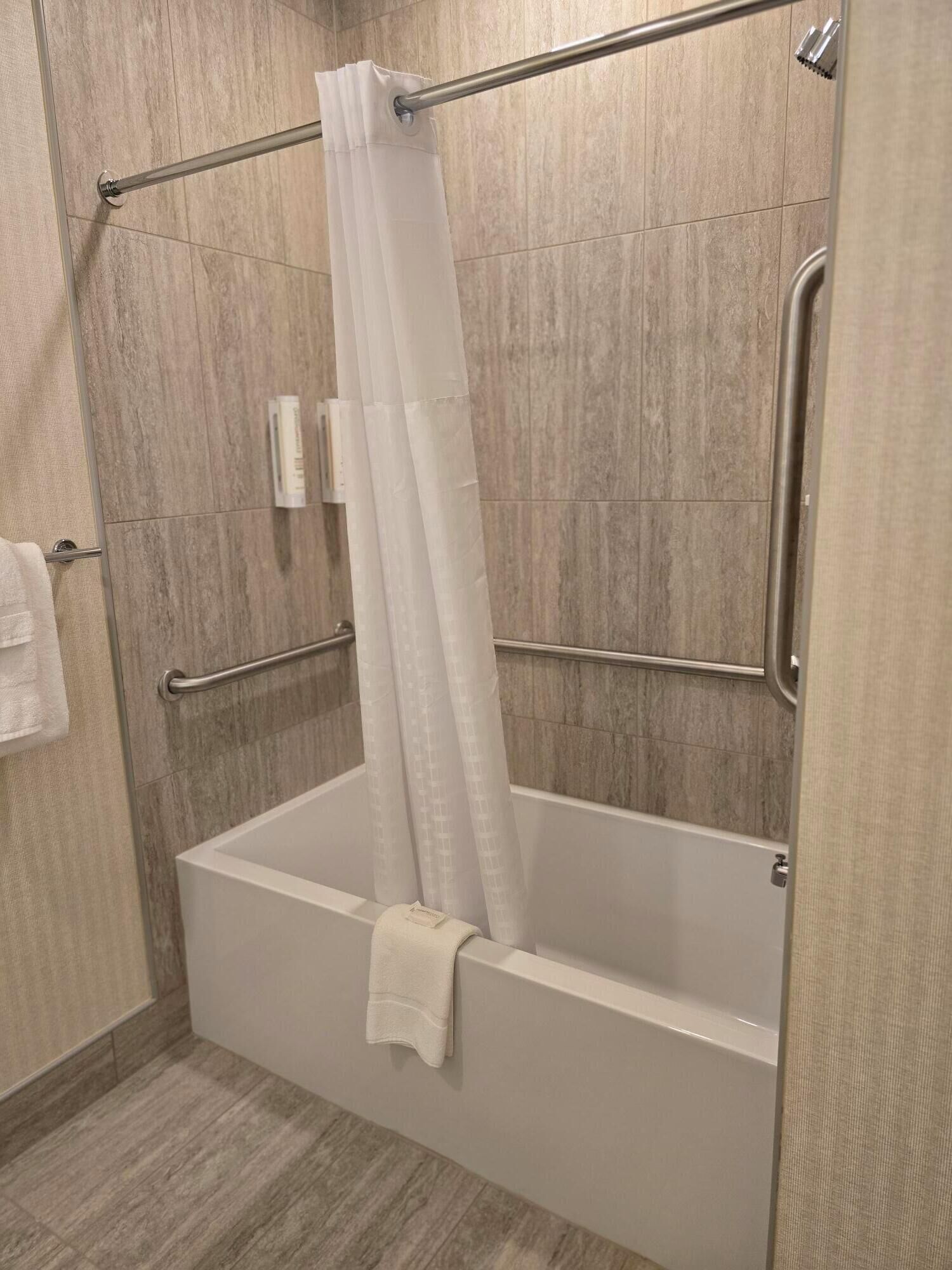 A modern bathroom with a walk-in shower, a glass door, and a towel rack.