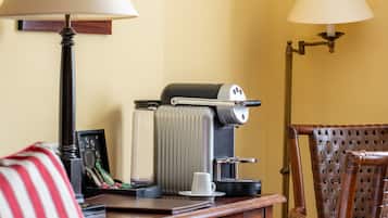 Ein Hotelzimmer mit einem Bett, einem Holztisch mit Kaffeemaschine, einer Lampe und einem Korbstuhl.