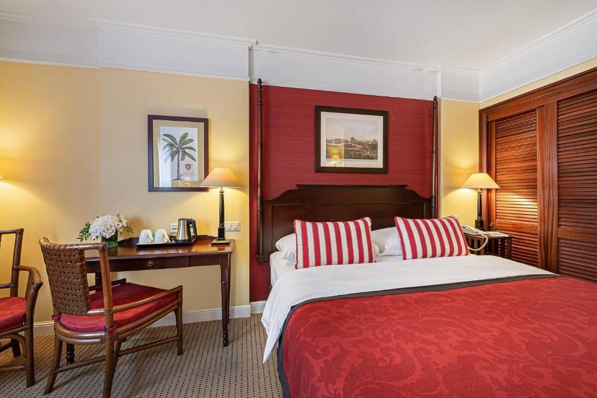 Een hotelkamer met een bed, een bureau, een stoel en een nachtkastje.