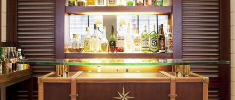 Una zona de bar con mostrador de madera y estantes llenos de botellas de licores.