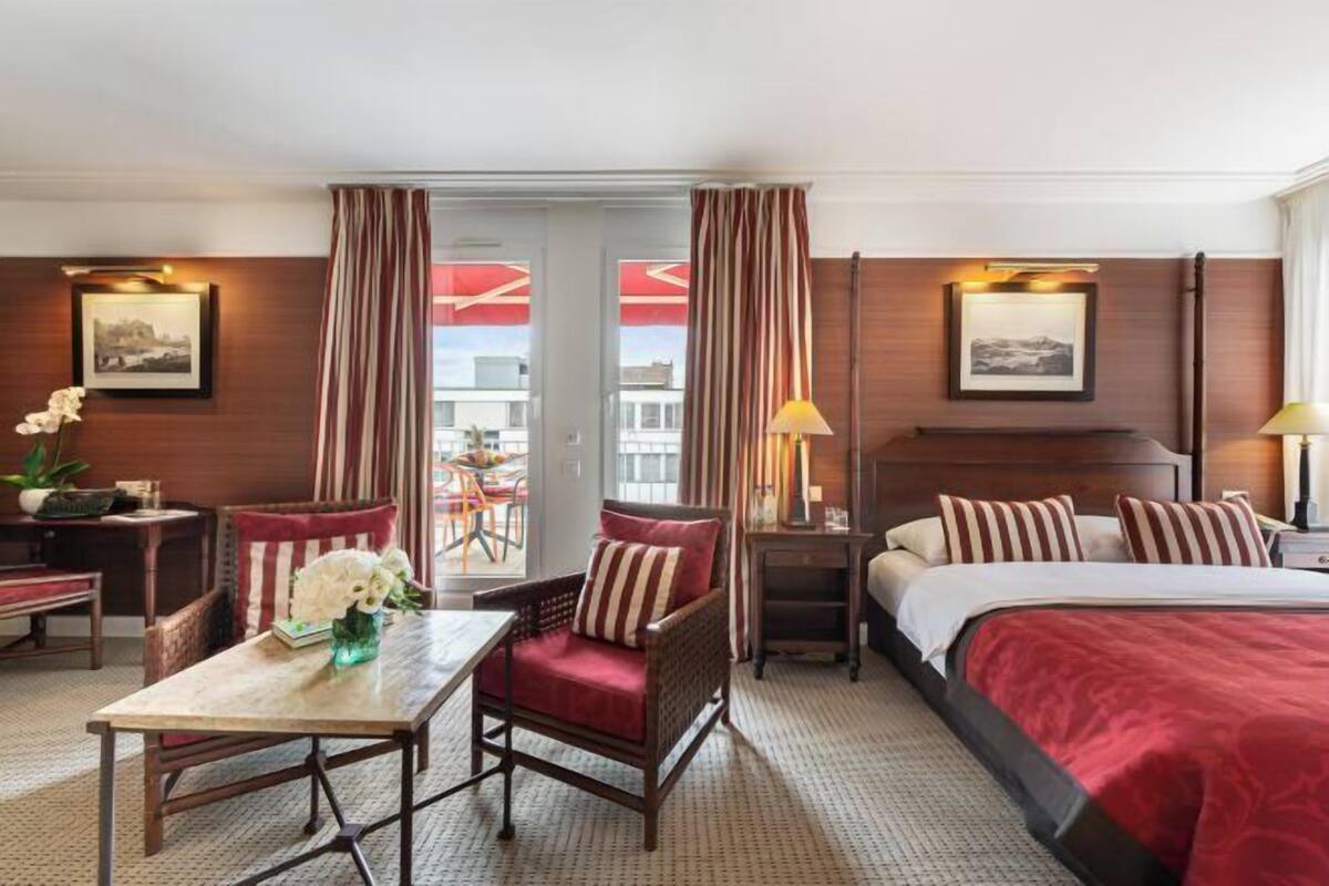 Een hotelkamer met een bed, een stoel, een tafel, een lamp en uitzicht.