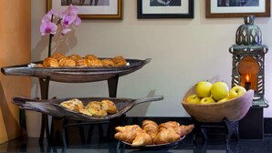 Una mesa con pasteles y un bol de manzanas, con fotografías enmarcadas en la pared de fondo.
