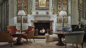 Una sala dall'atmosfera formale, con camino, opere d'arte incorniciate e arredi classici.