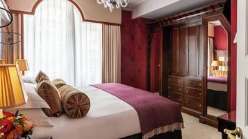 Une chambre d’hôtel avec un grand lit, un lustre, une armoire et un miroir.