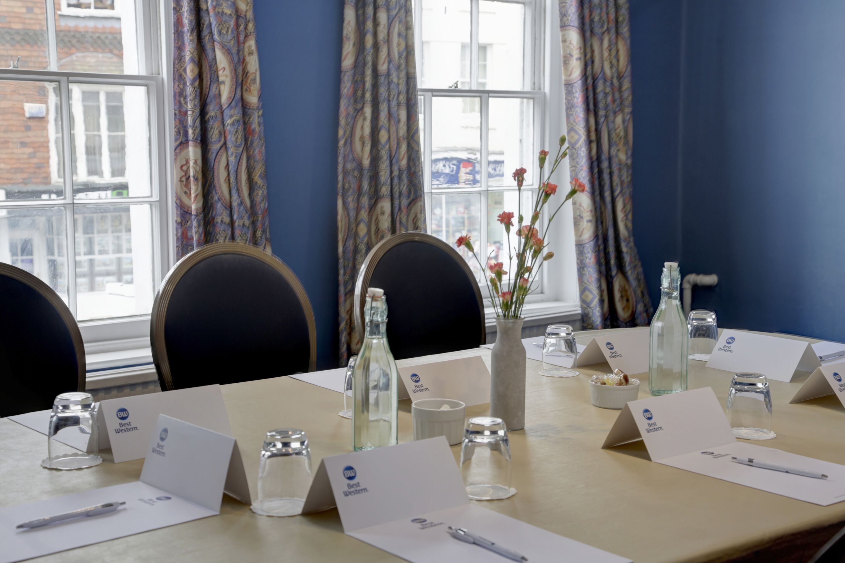 A conference room with a long table, name cards, and glassware.