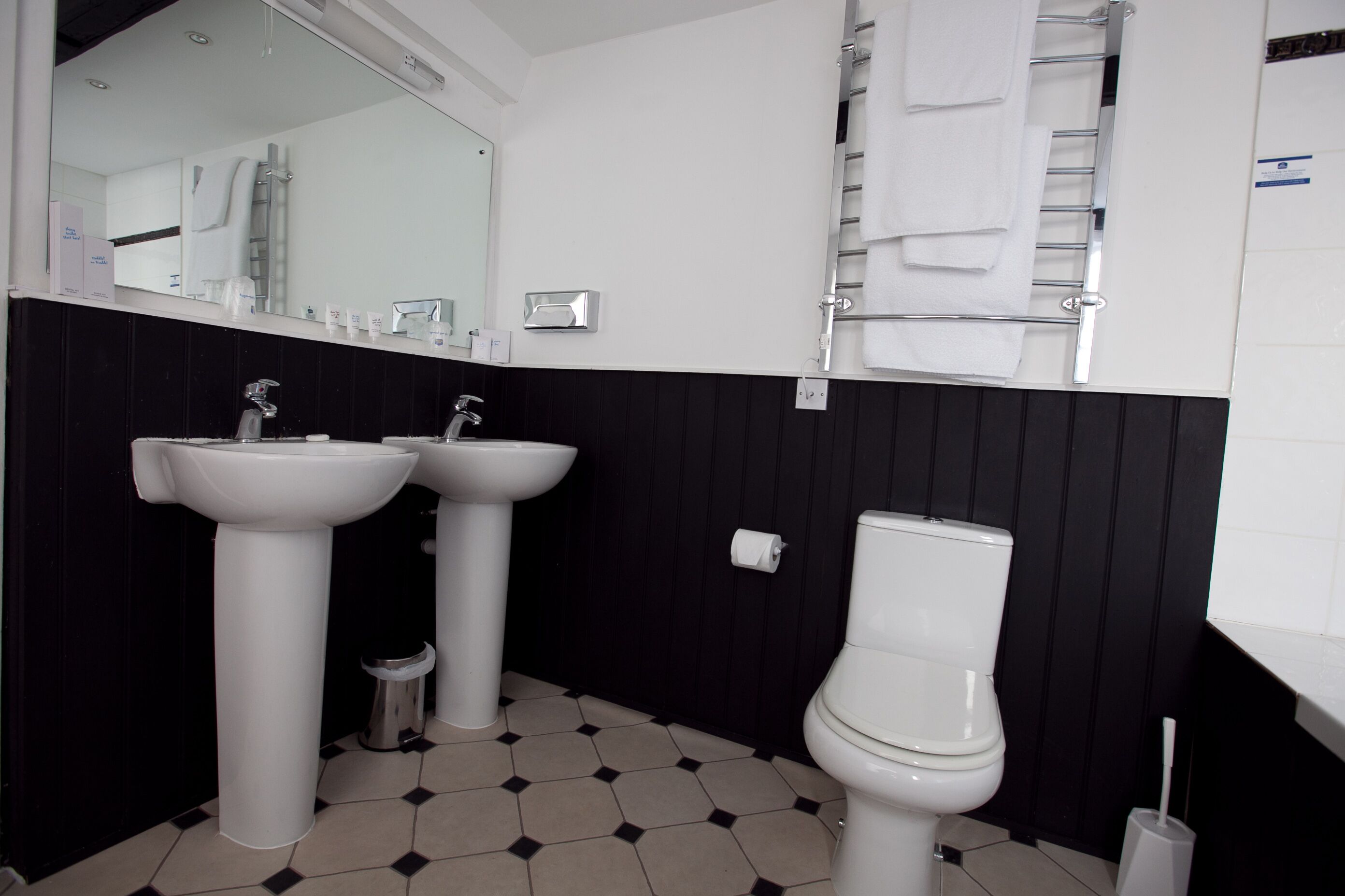 A bathroom with two sinks, a toilet, and a towel rack.