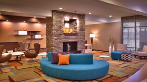 A modern lounge area with a stone fireplace, comfortable seating, and a colorful carpet.