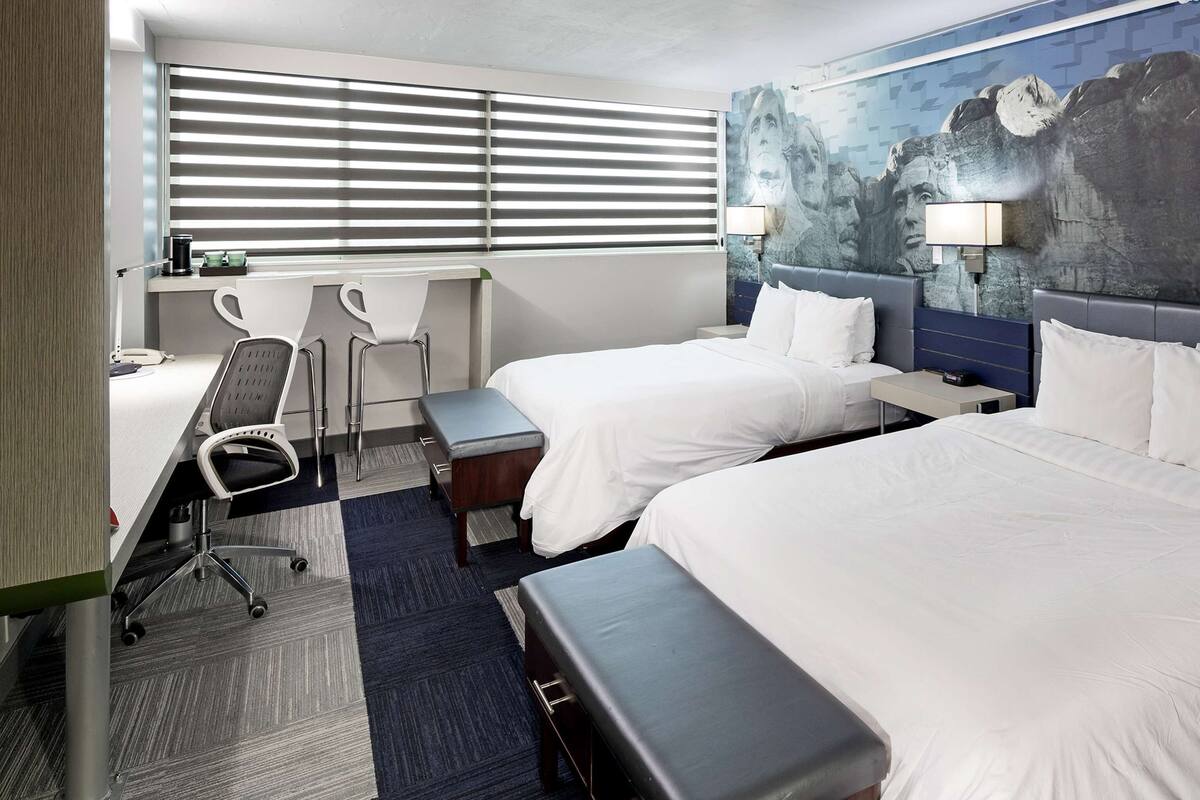 Une chambre d’hôtel avec deux lits, un bureau et une chaise.