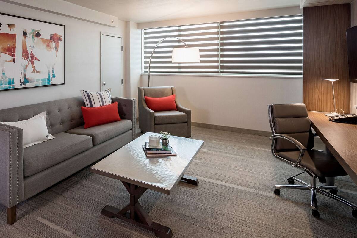 Un espace de bureau moderne avec un canapé gris, une table basse, un bureau et une chaise.