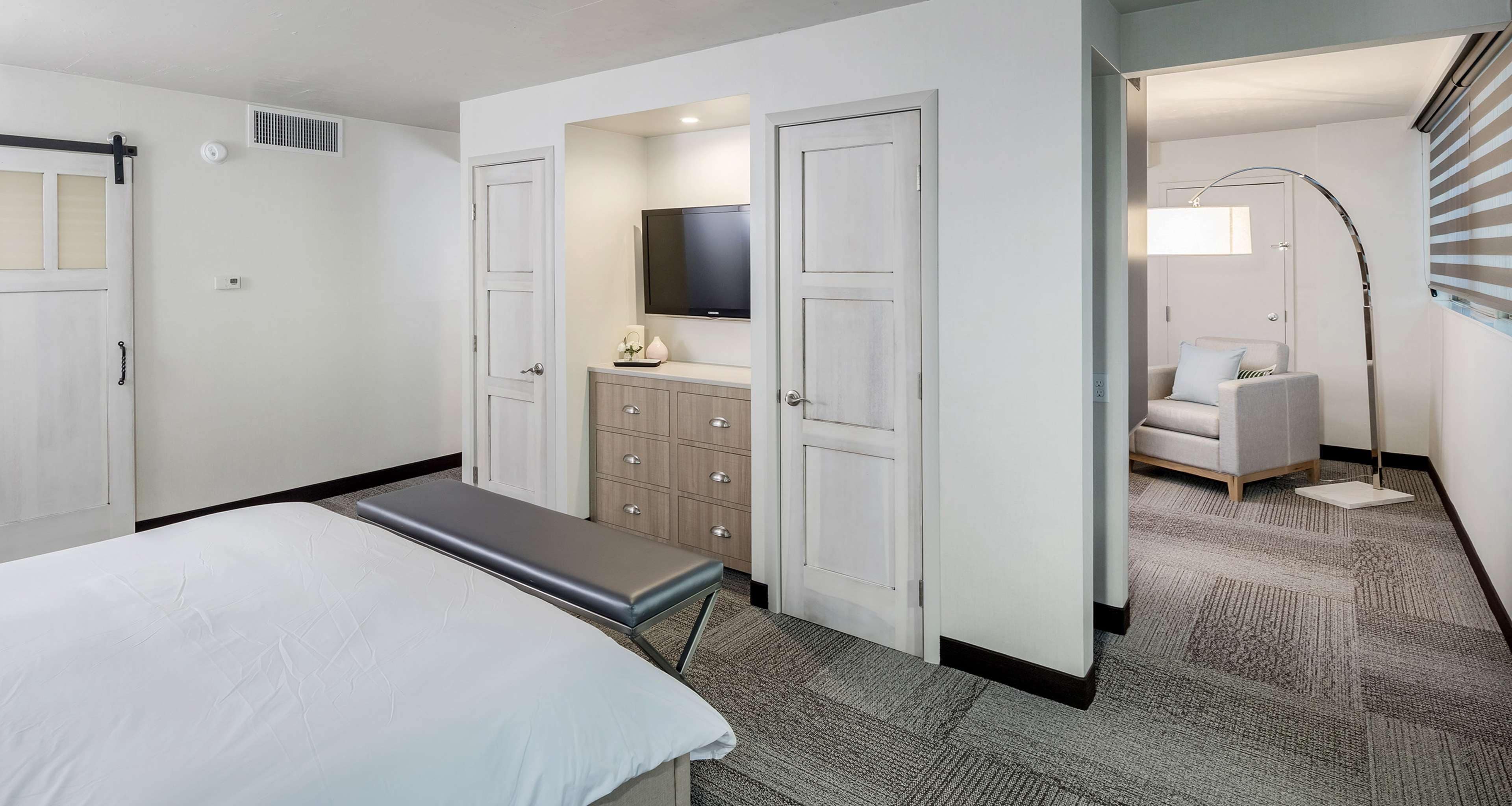 Een hotelkamer met een bed, bureau, televisie, kast en badkamer met douche en toilet.