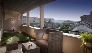 A balcony with a pool table, wicker furniture, and a view of city buildings.