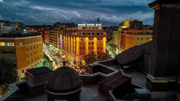 A cityscape at dusk with a prominent Grand Hotel Ritz building.