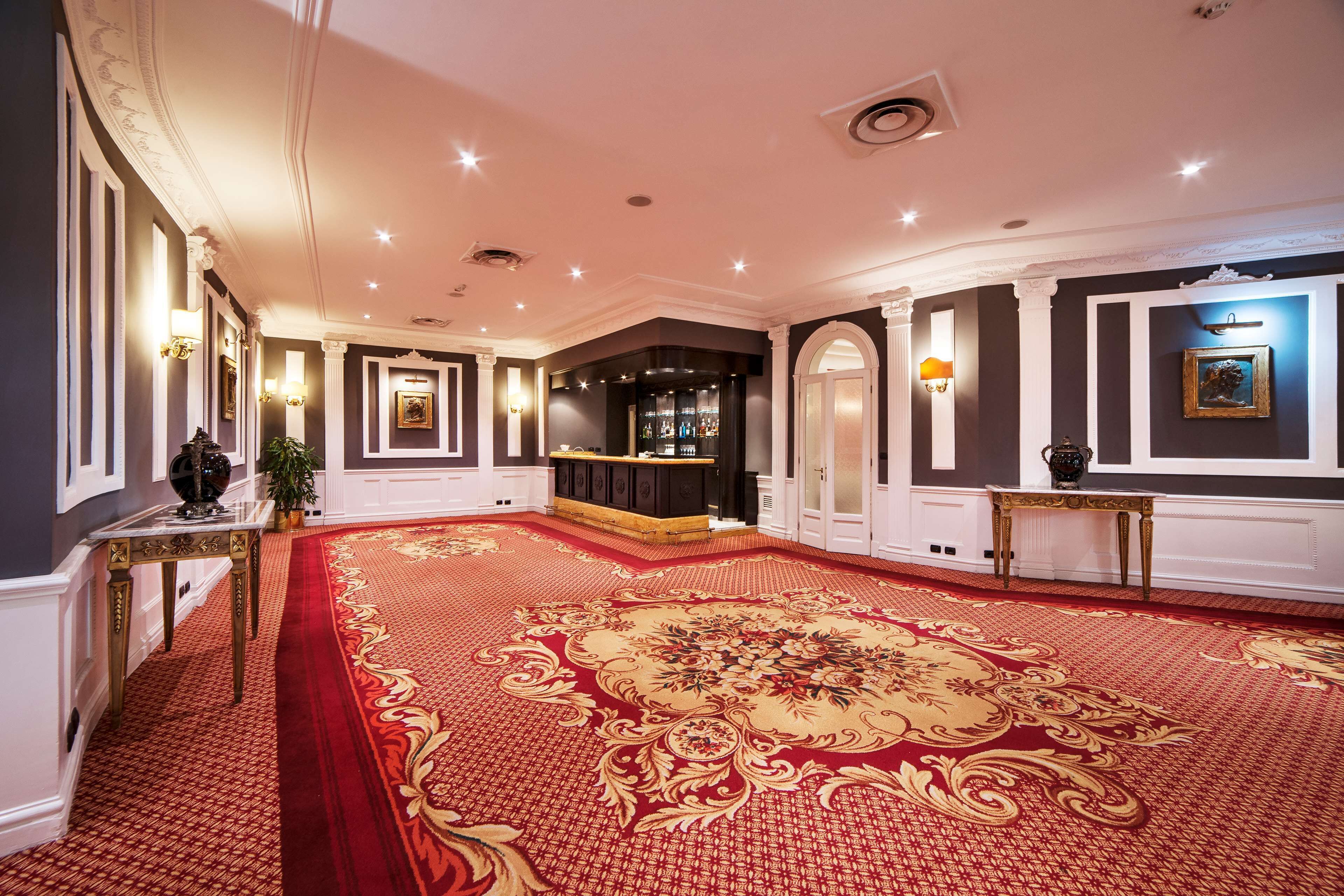 A grand hallway with a red carpet, ornate wall decorations, and a bar area.