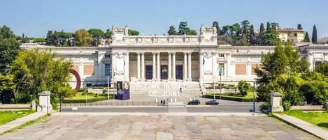 A grand building with classical architecture, featuring a central staircase leading to an entrance.