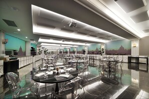 A spacious dining area with multiple tables and chairs, a modern ceiling design, and a mural on the wall.