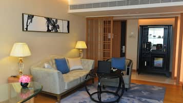 A modern living room with a sofa, two lamps, a glass coffee table, and a small table with a vase.