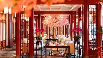 Un hall d’hôtel avec une table centrale, des espaces aménagés pour s’asseoir et un arbre décoratif.