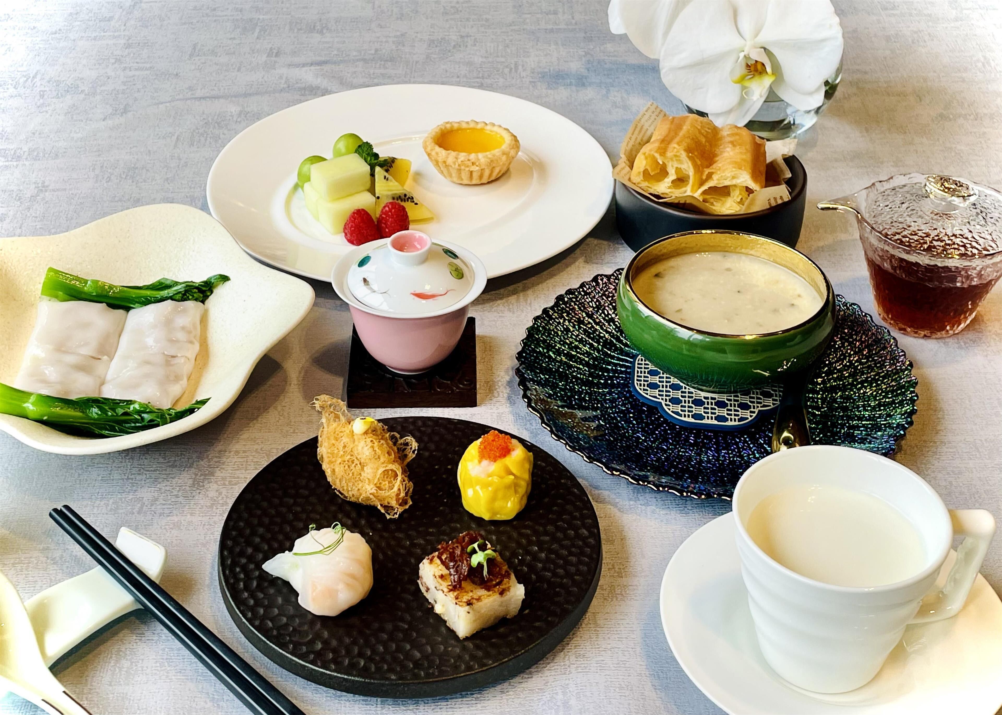 Variedad de platos y bebidas sobre una mesa, incluyendo un tazón de sopa, un plato con dumplings y una taza de té.