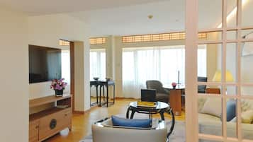 Uma sala de estar moderna com televisão de tela plana, sofá, mesa de centro e área de jantar com mesa e cadeiras.