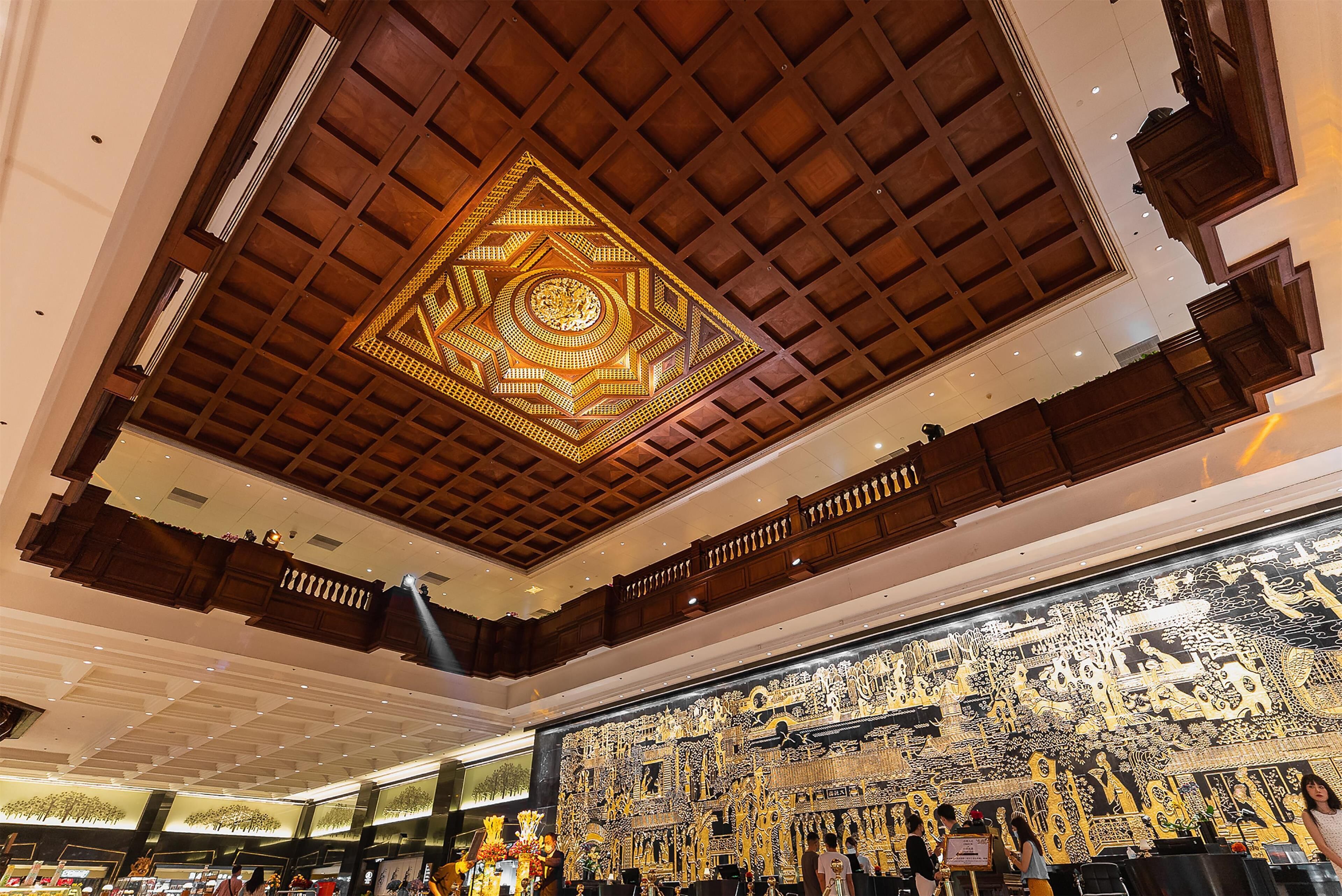 Interior de hotel com teto alto de madeira, decoração de parede elaborada e uma varanda.