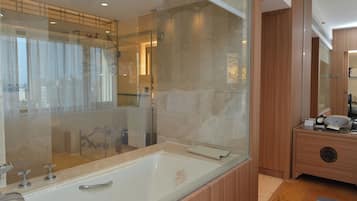 Un baño moderno con una bañera grande, cabina de ducha de vidrio y muebles de madera.