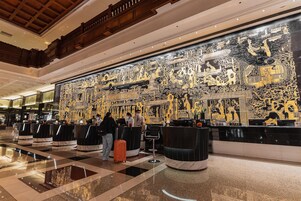 A lobby with a checkered floor, reception desks, and a large decorative wall.