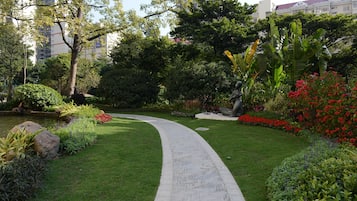 Un jardín ajardinado con un sendero sinuoso, diversas plantas y un estanque.