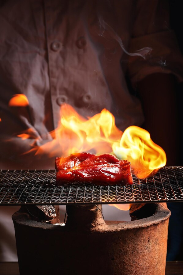 Un gril sur lequel de la viande est en train de cuire au-dessus d’une flamme nue.