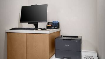 A desk with a computer monitor, keyboard, mouse, and a Brother printer on a white counter.